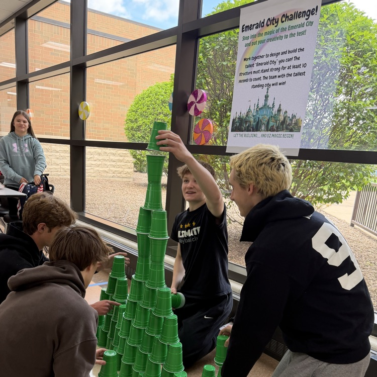 students in front of a poster with challenge instructions and a tower