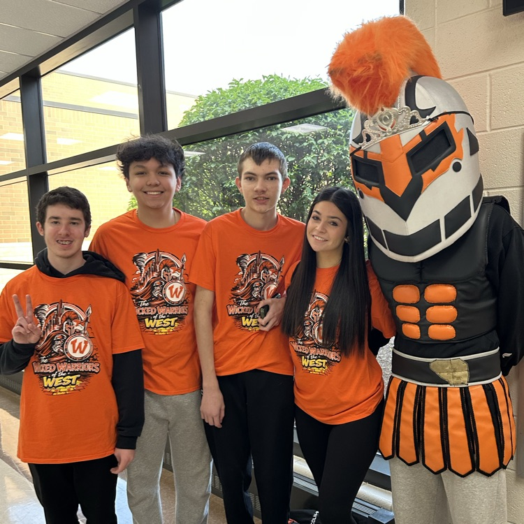 four students wearing orange shirts with the mascot