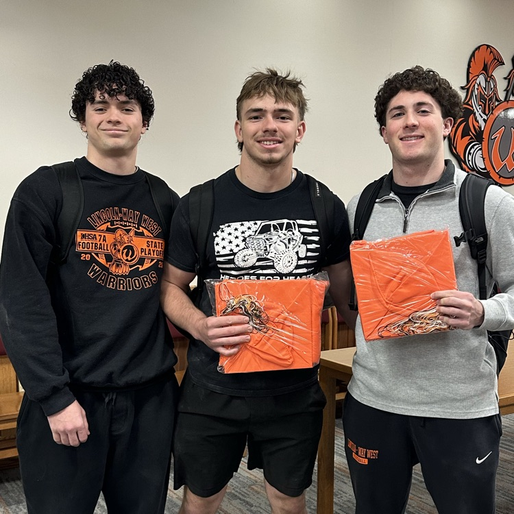 three students with two of them holding their caps and gowns