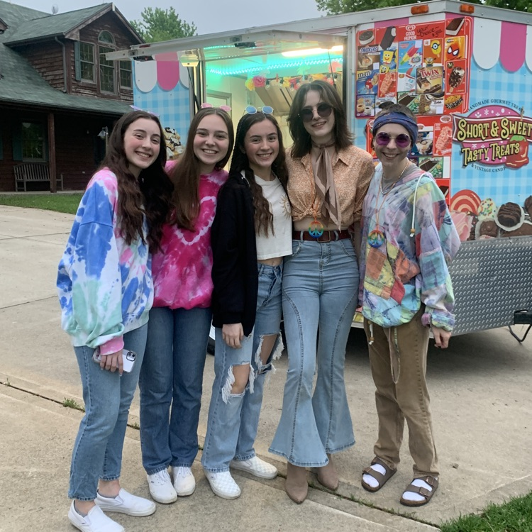 students in 70s attire posing in front of a food truck