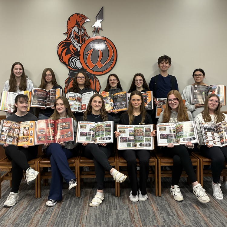 two rows of students holding the yearbook open