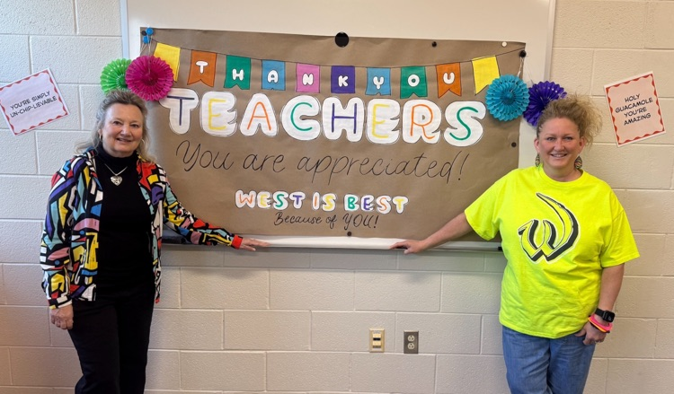 two staff posing in front of a banner