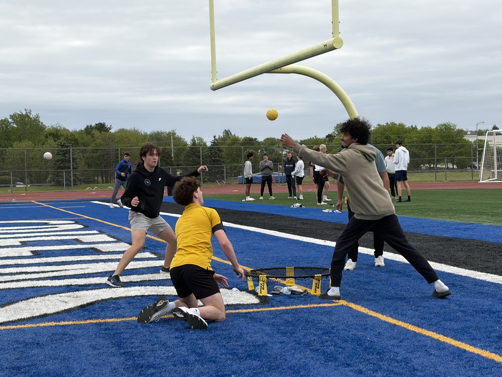 On a football field, players engage in a game. A person throws a ball, while another attempts to catch it.