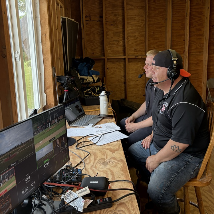 student and adult in press box with head gear on