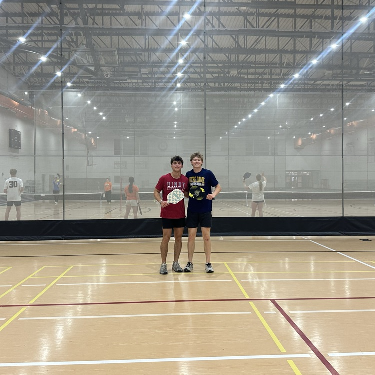 two students posing with pickleball paddles