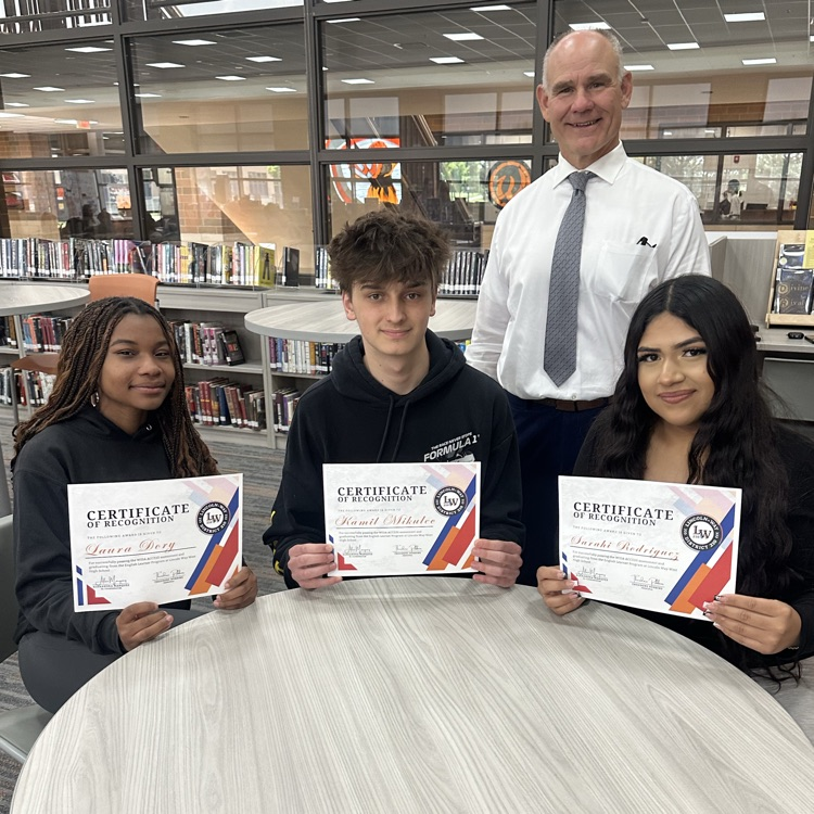 three students holding certificates with the principal for a photo