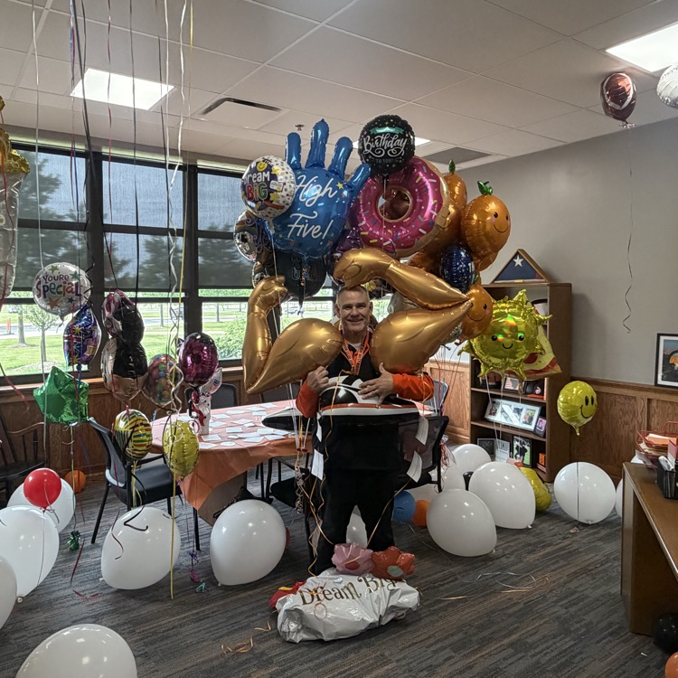 principal with a number of balloons in his office