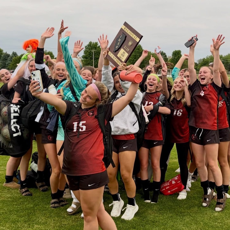 girls soccer team posing for a selfie with the regional trophy