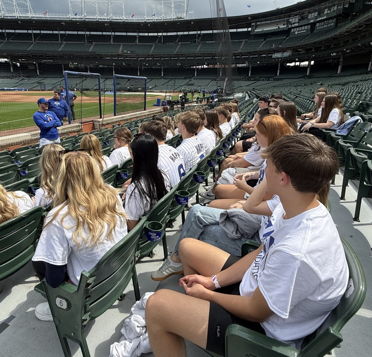 students listening to presentation in field bleachers