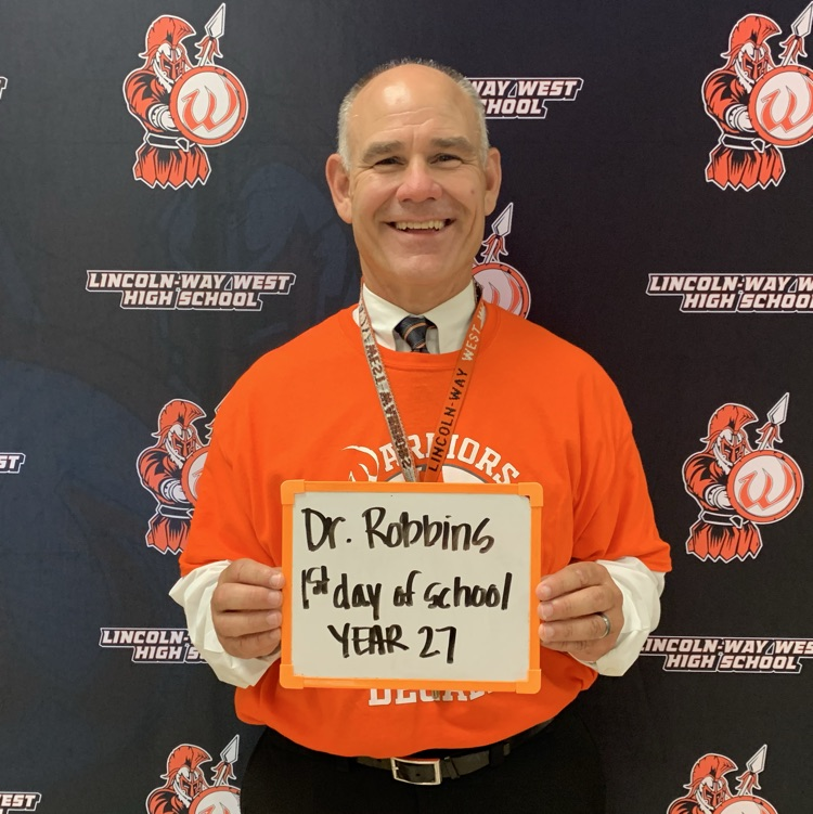 principal holding sign about first day of school