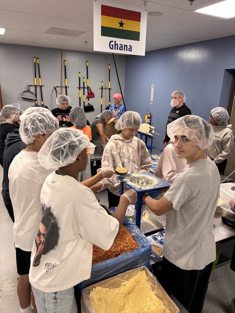 A group of people wearing hair nets in a kitchen.