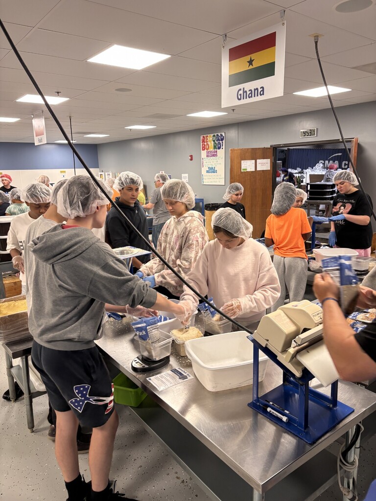 Group of people wearing hairnets preparing food in a kitchen.