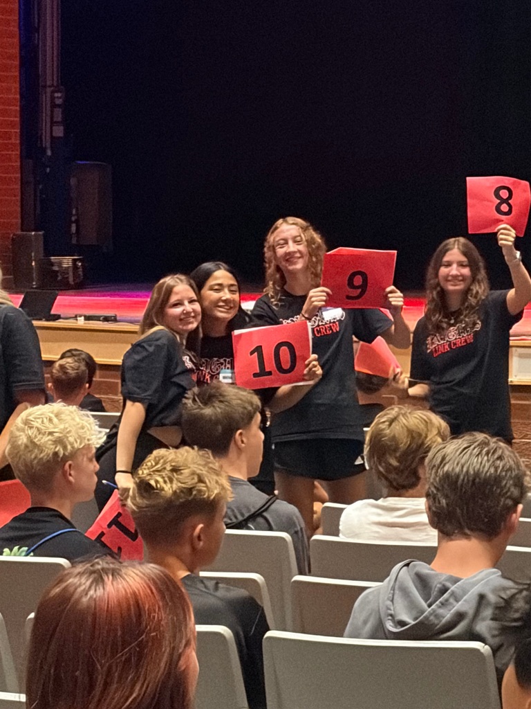 Four girls smiling and holding red signs with numbers on them