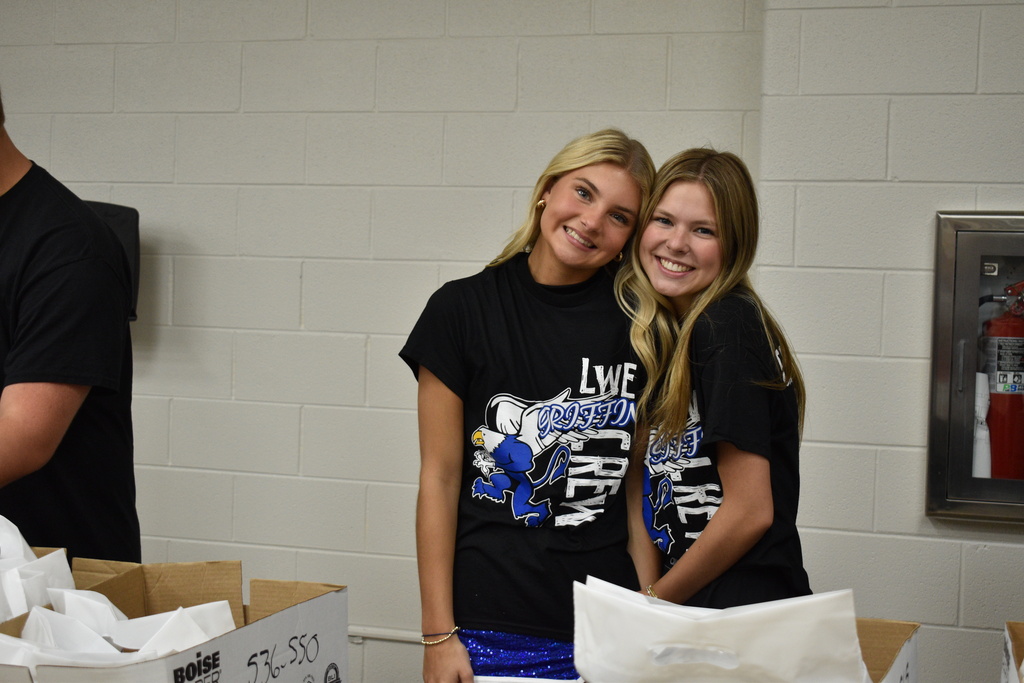 Two women in matching shirts smile at the camera.