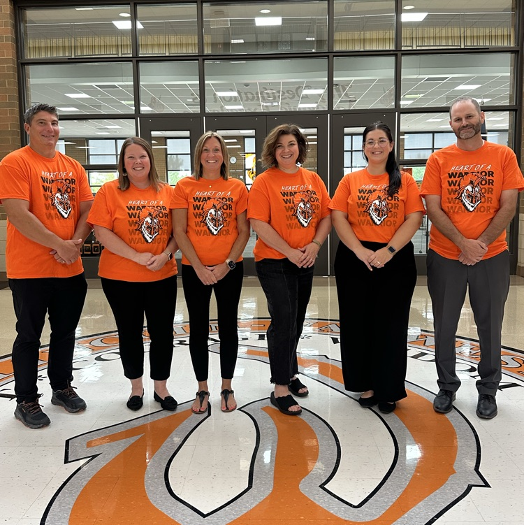 admin team wearing heart of a warrior shirt in front of library