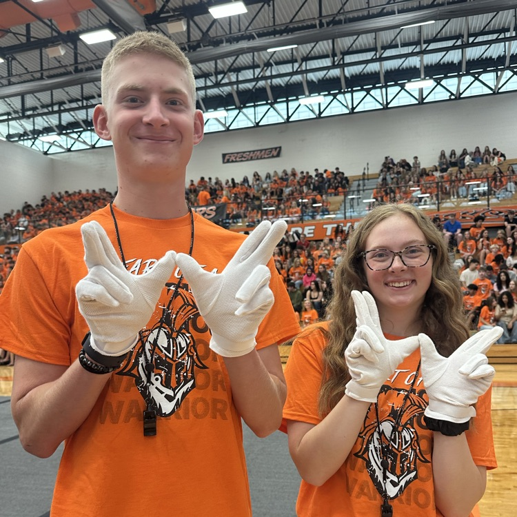 two students posing with Ws