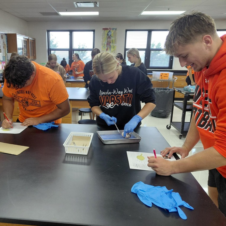 three students at a lab table working on the lab and making notes