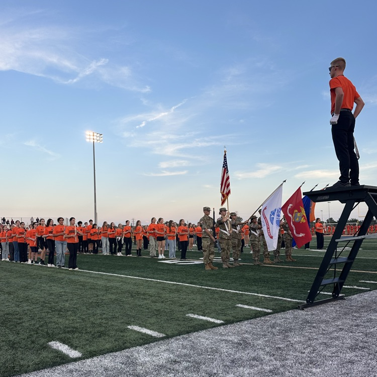 drum major leading the national anthem on the stadium field