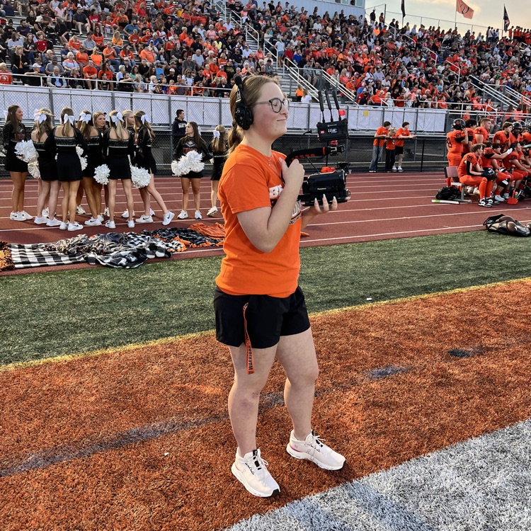 student filming the football game from the sidelines