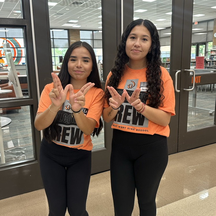 two students in front of the library posing with a W