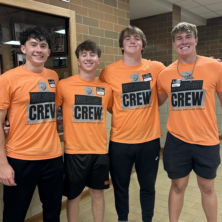 four students posing for a photo in their welcome crew shirts