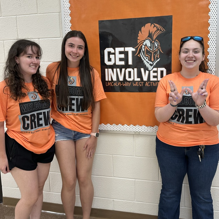 three students standing in front of get involved bulletin board