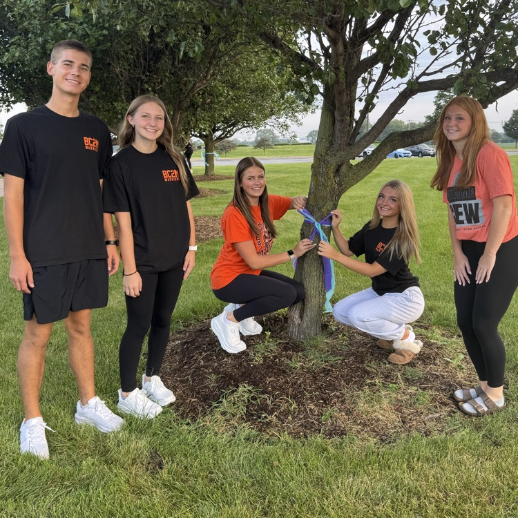 students posing in front of a tree