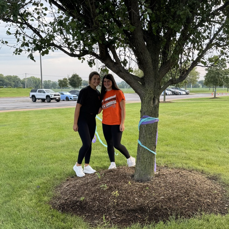 two students wrapping ribbon around a tree