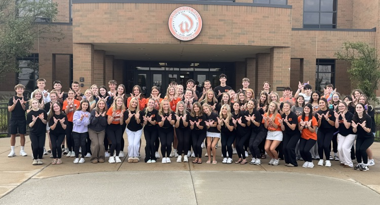 large group of students standing in front of school building
