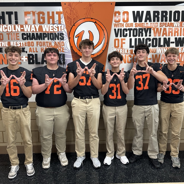 students in football jerseys holding up Ws