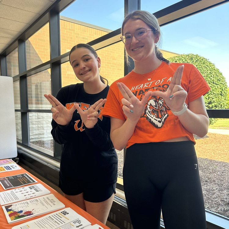 students posing in front of flyers with a W
