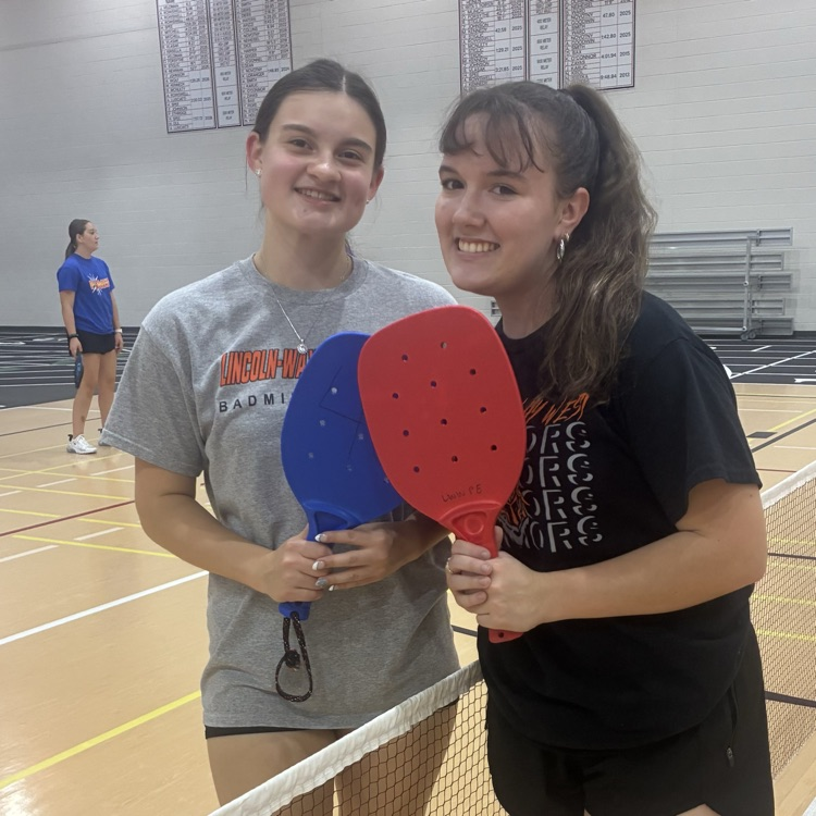 students posing for a photo with pickleball paddles