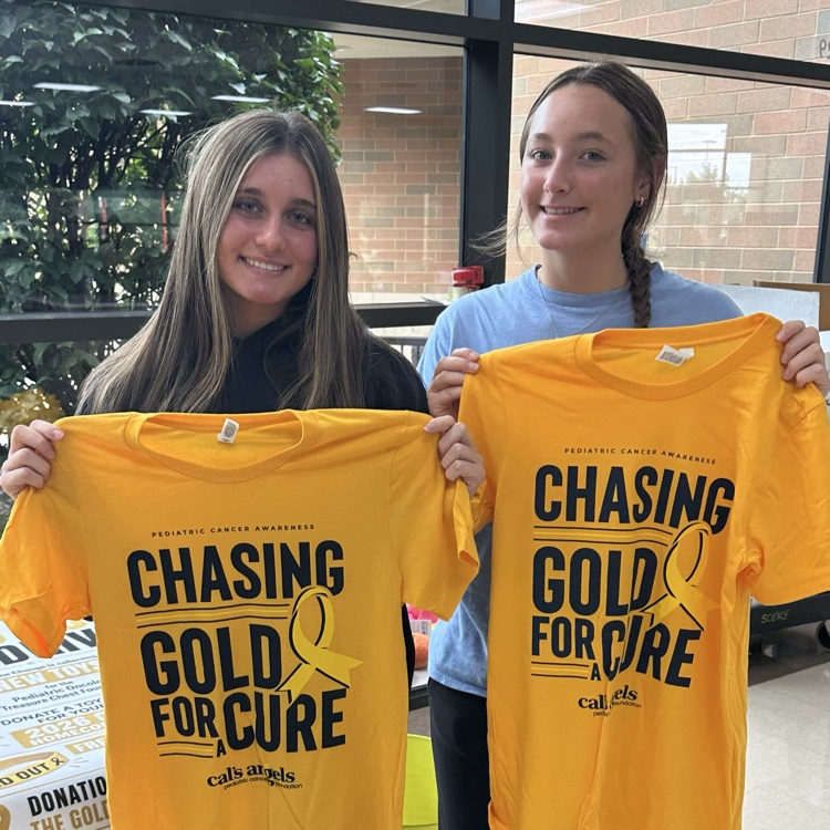 students holding yellow chasing gold t-shirts