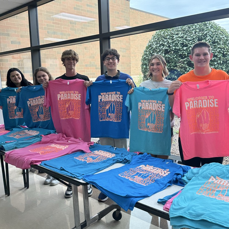 students holding paradise shirts in the cafeteria