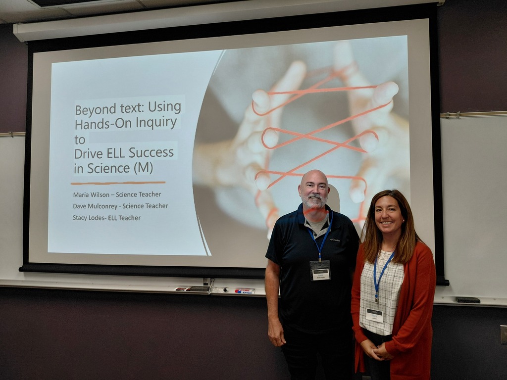 Teachers posing for a photo with a presentation screen behind them