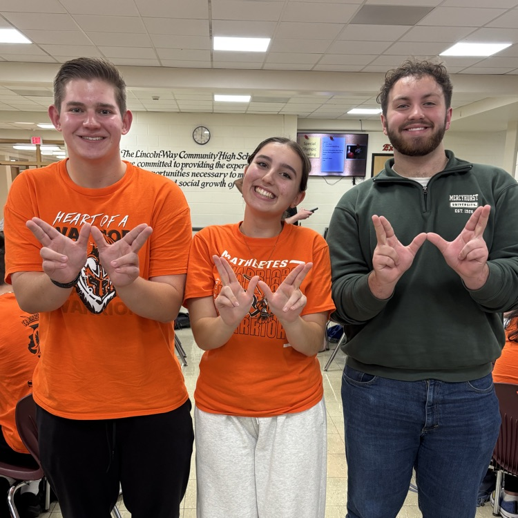 three students holding Ws at competition