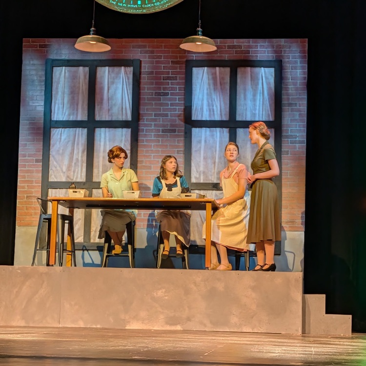 students at table acting on stage