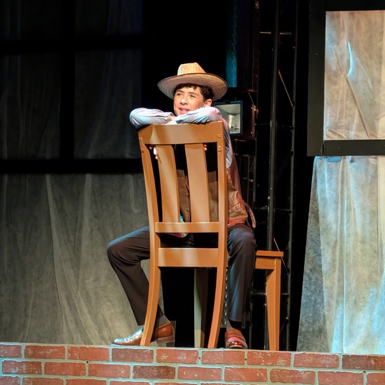 student sitting in chair on stage