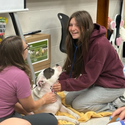 student and teacher with dog in classroom