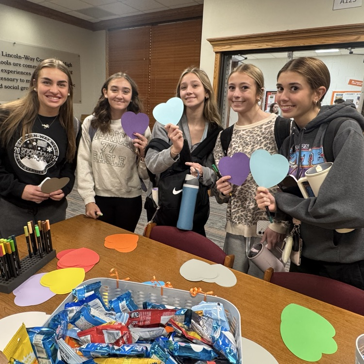 students at the start of a club meeting in front of supply table