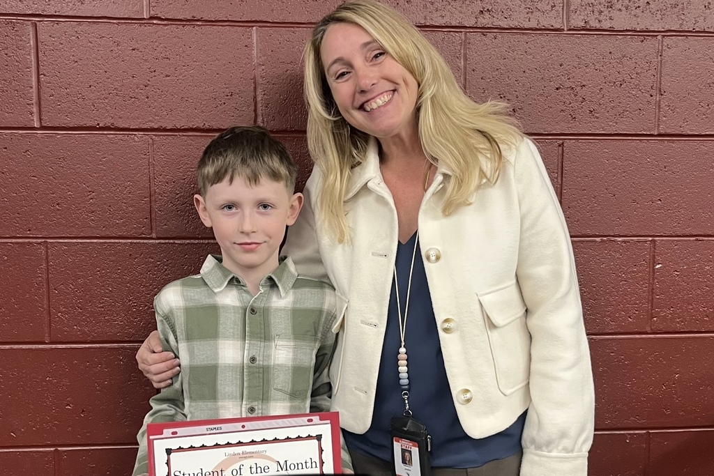 Male student holding certificate with female teacher.