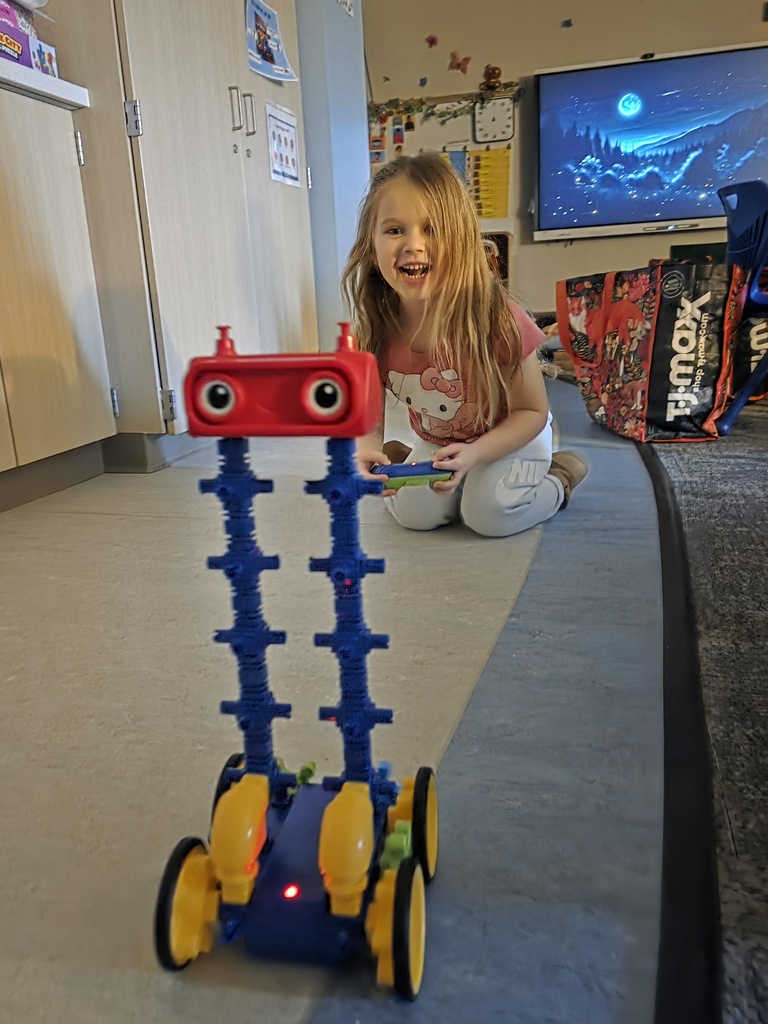 A student at LCS Early Childhood Center showing off a creative STEM project made of interlocking plastic gears and blocks.