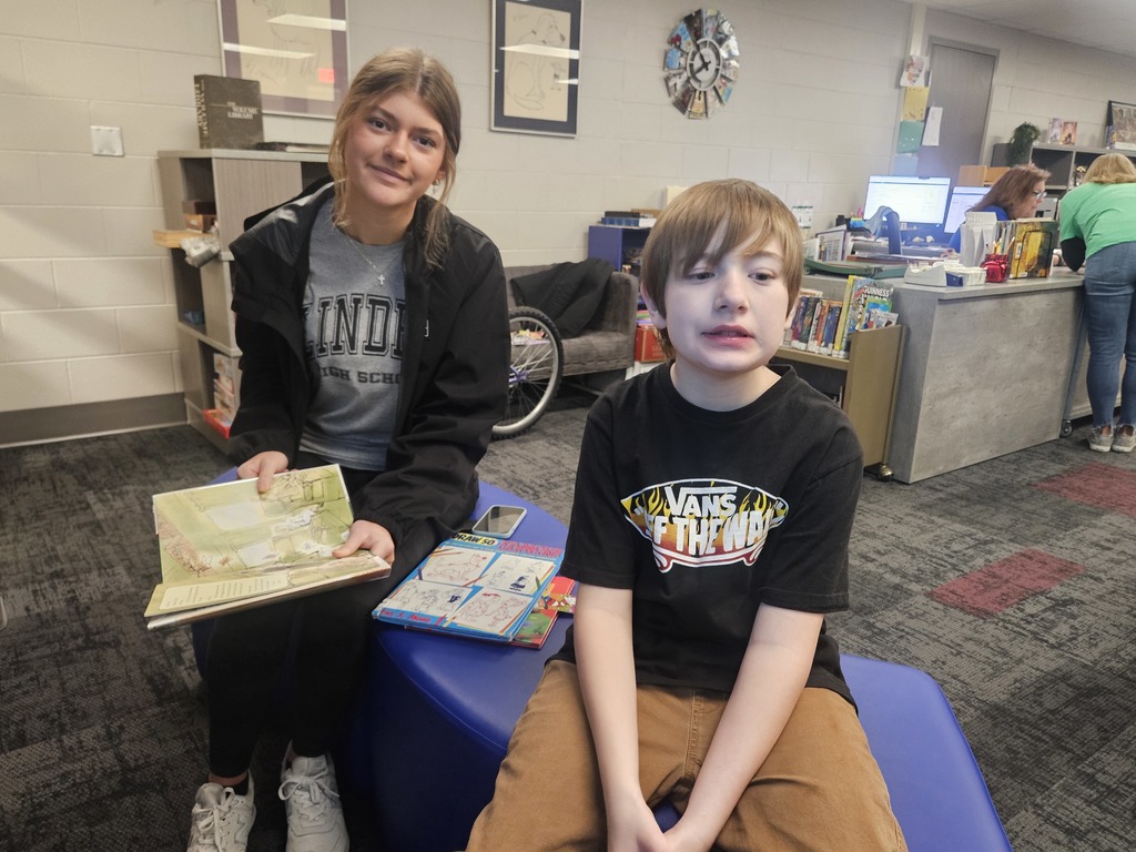 High School Student reading to a student in elementary school.  