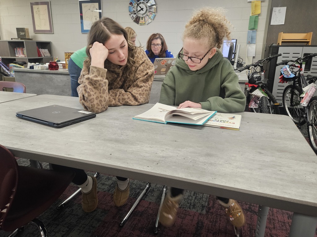 High School Student reading to a student in elementary school.  