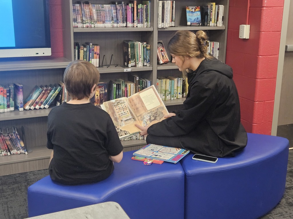 High School Student reading to a student in elementary school.  