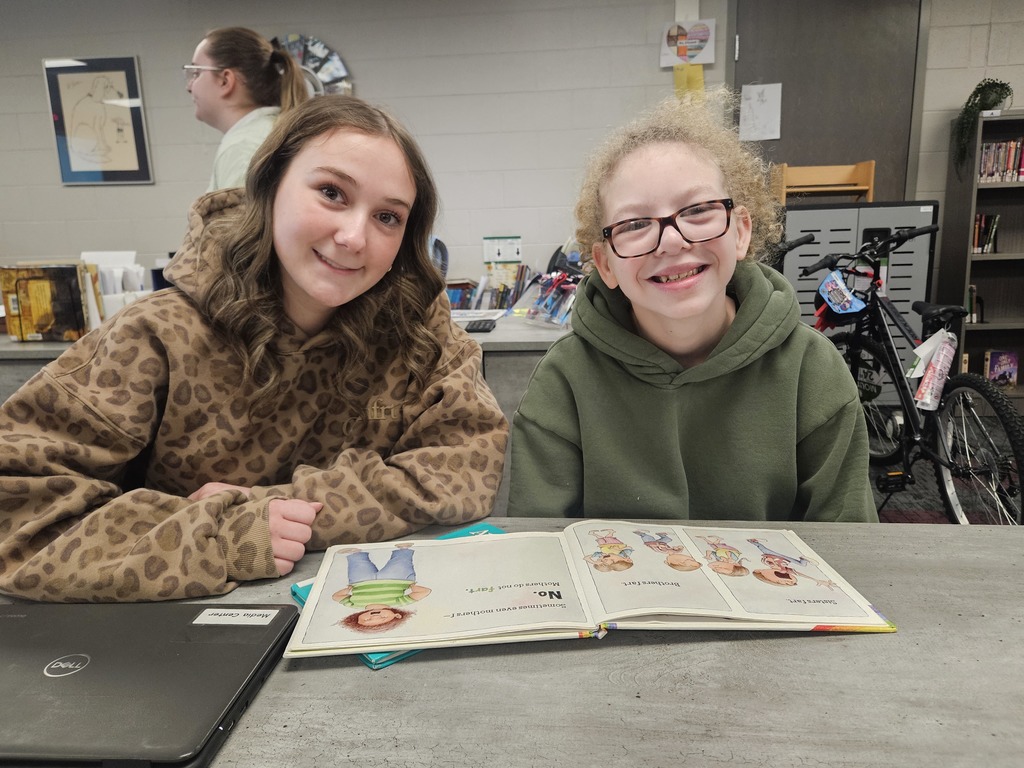 High School Student reading to a student in elementary school.  