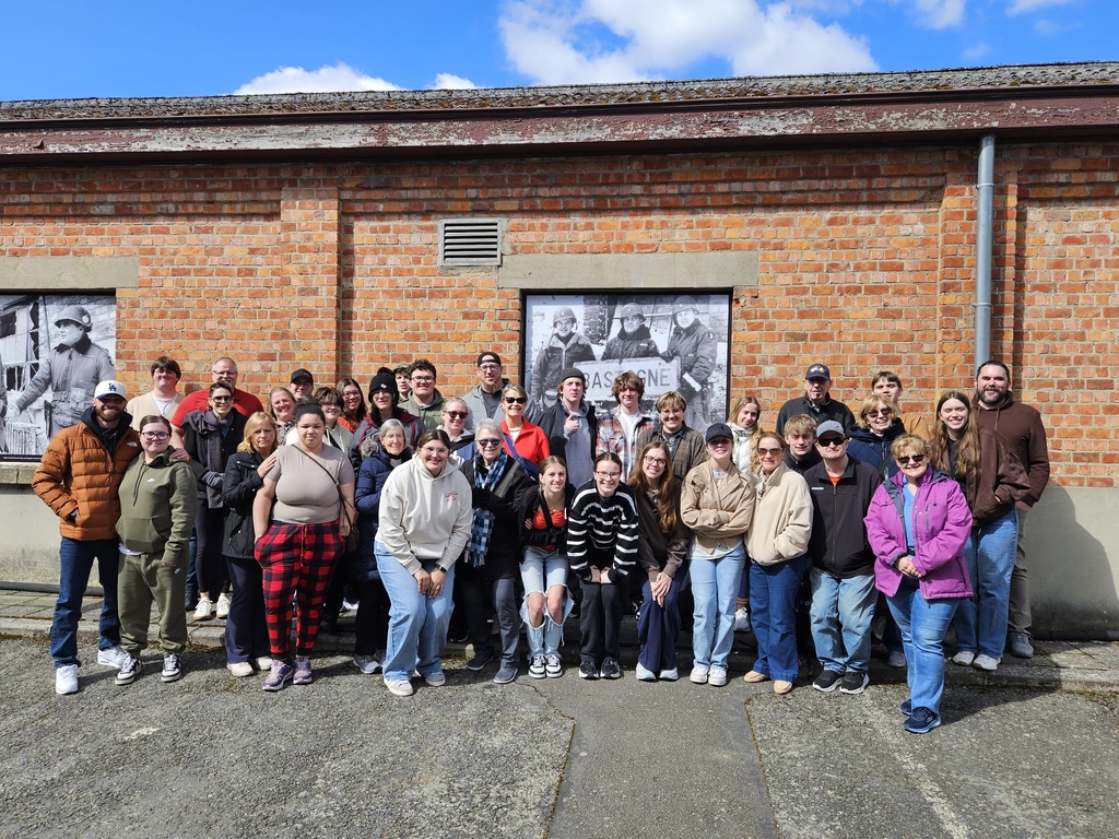 Group of students standing in front of a WWII barracks in Bastogne Belgium