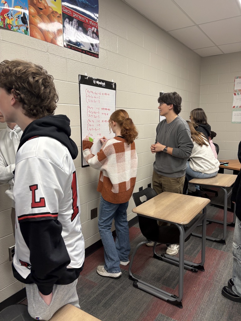 Students writing on vertical white boards