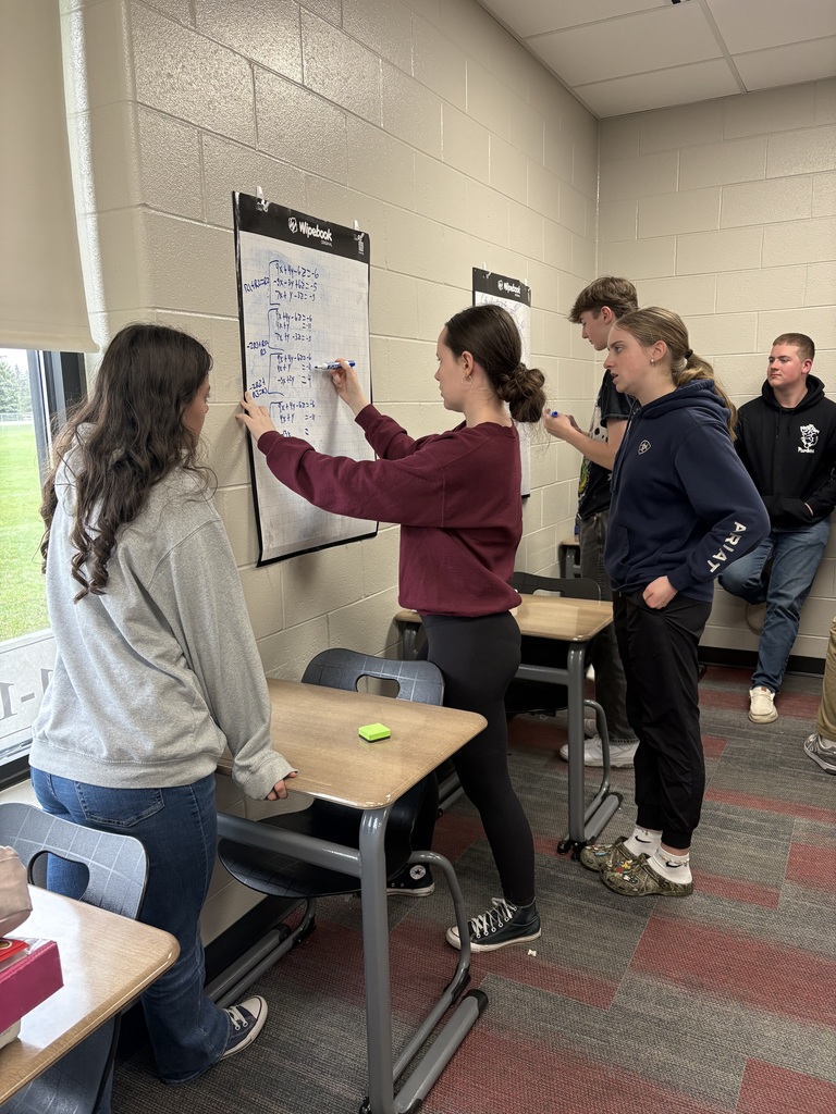 Students writing on vertical white boards