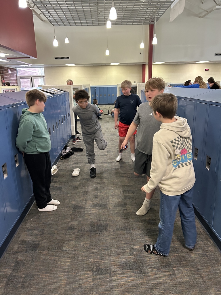 One boy is showing another boy the pose he needs to hold while being timed. 